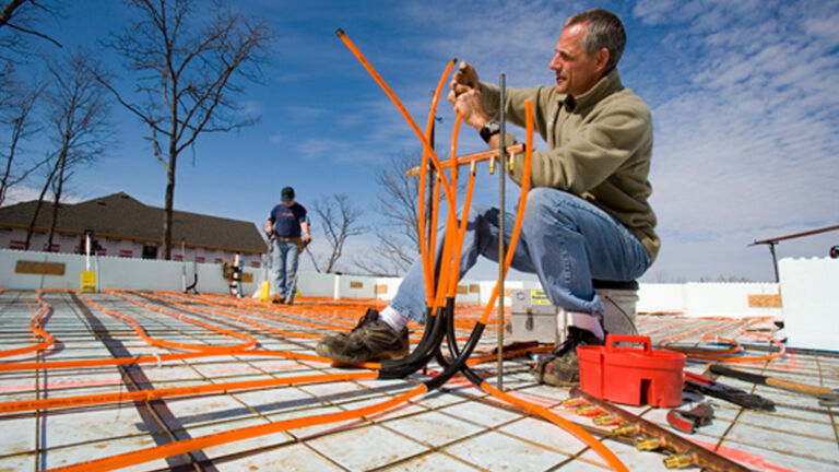 radiant heat being installed by a man sitting on a bucket