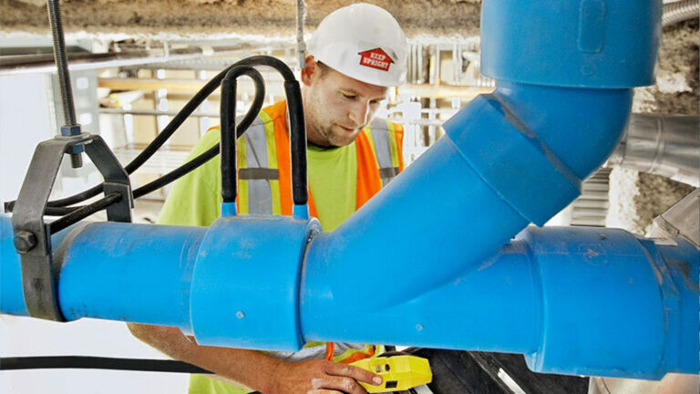 Photograph of mechanical contractor installing Orion Blueline chemical waste piping